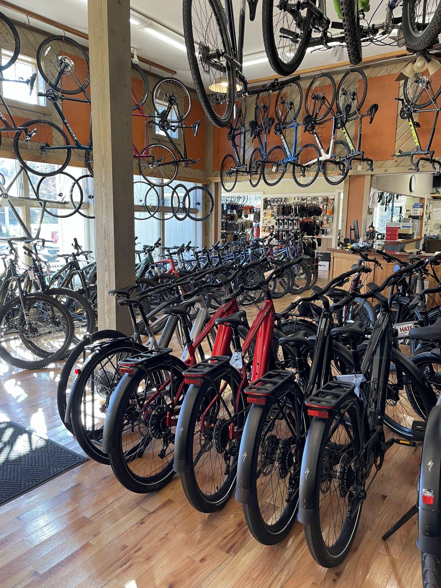 Several bikes lined up and hanging from the ceiling inside of Bar Harbor Bicycle Shop.