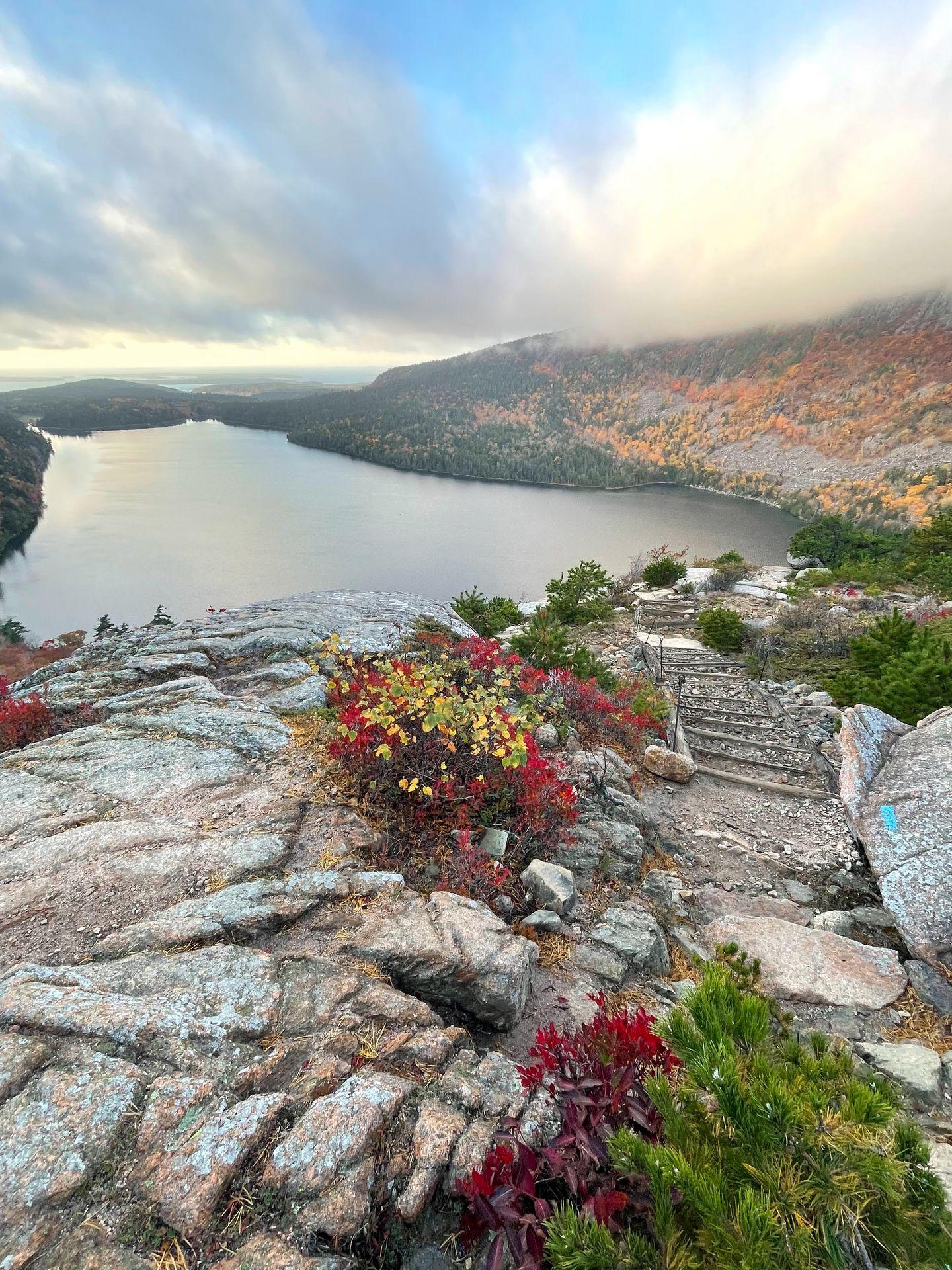 Looking down at Jordan Pond, which is surrounded by fall foliage.