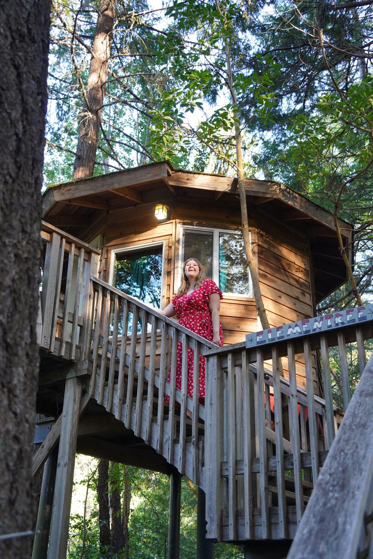 Lydia standing on the steps in front of a treehouse at Out N About Treesort