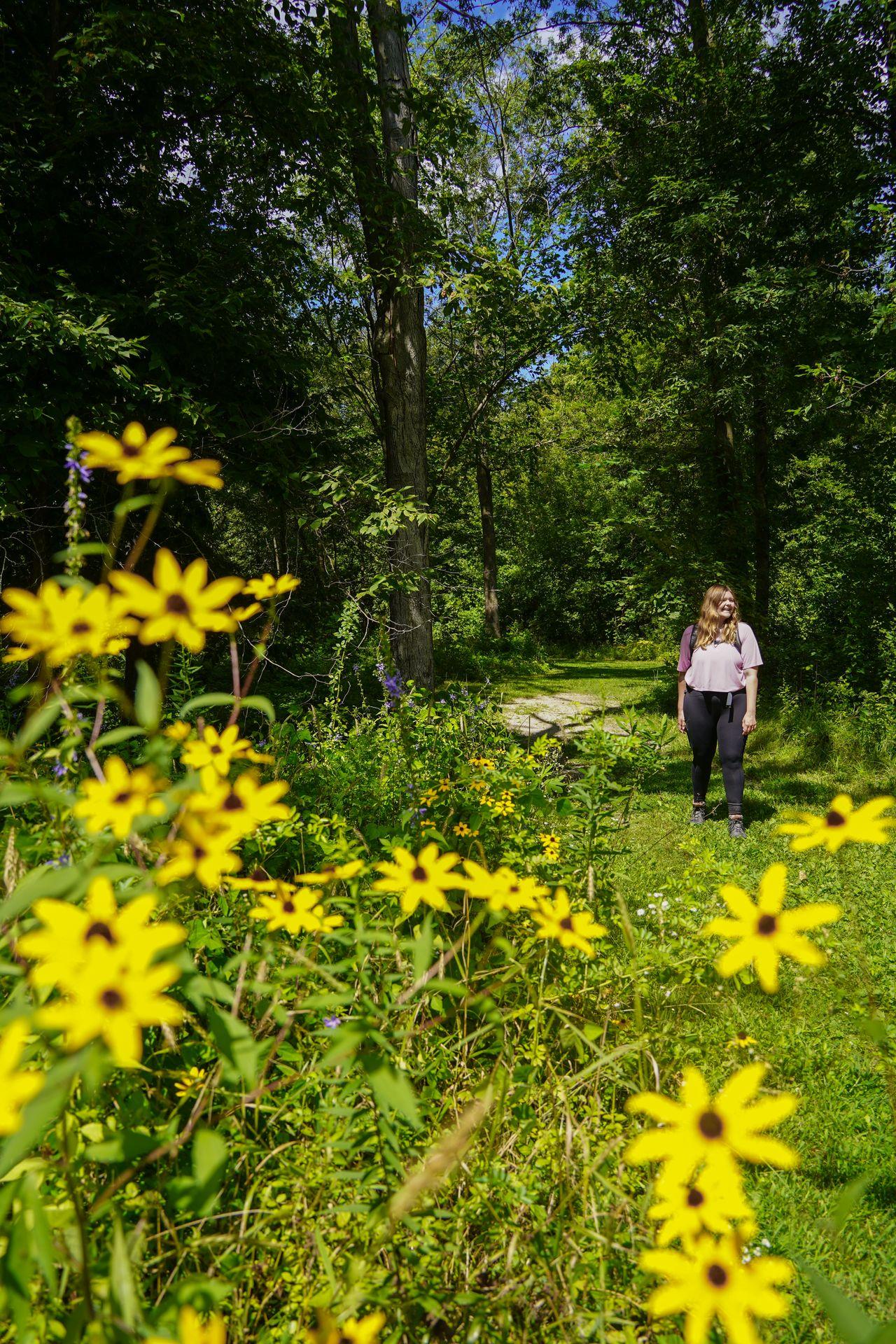 Lydia standing next to yellow flowers at Wickiup Hill Learning Center