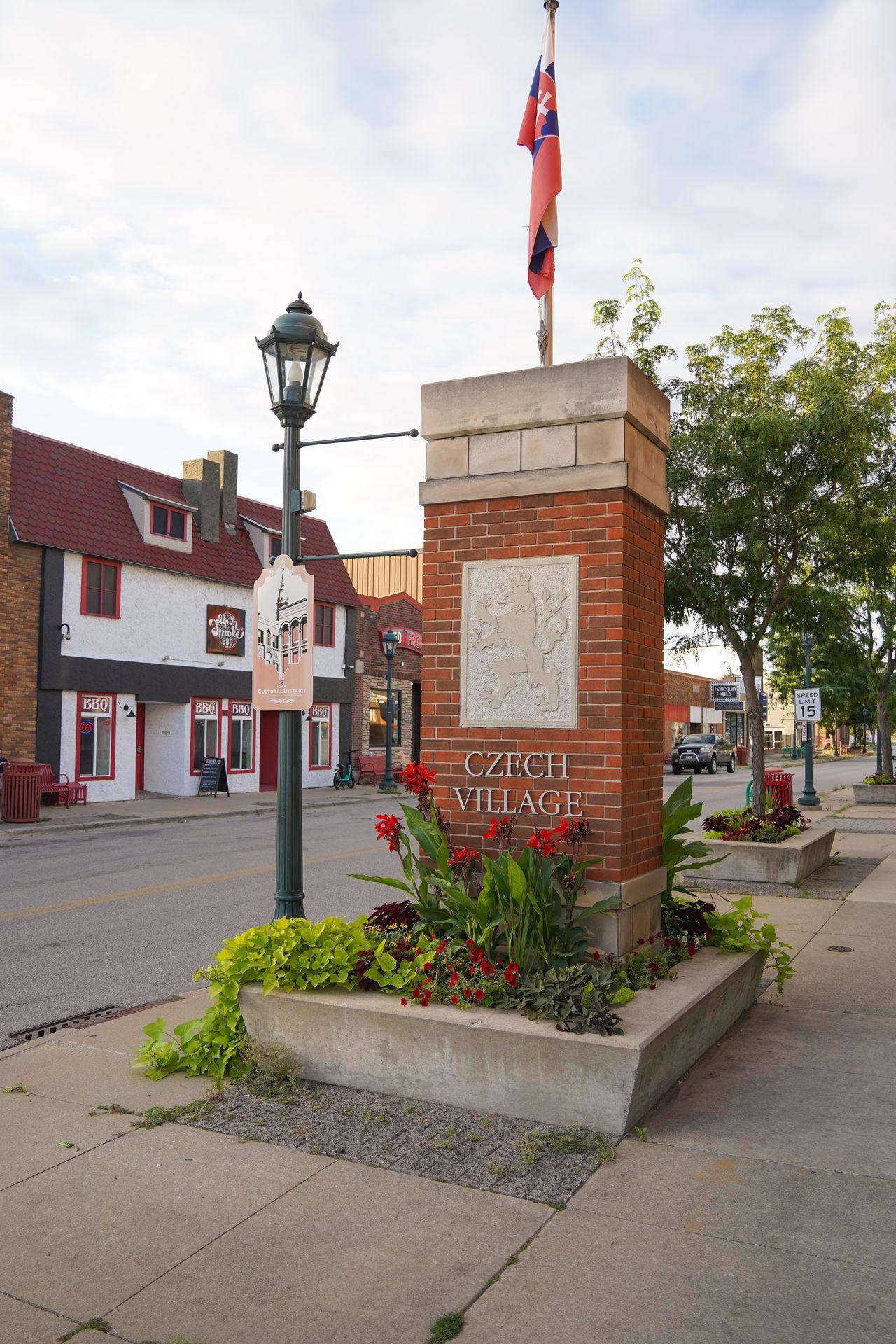 A pillar that reads 'Czech Village.' It's made of brick with a lion carved in white rock.