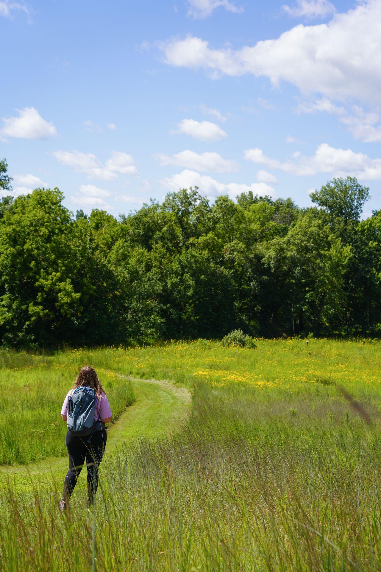 Lydia standing among grassy hills and tall grasses at Wickiup Hill Learning Center