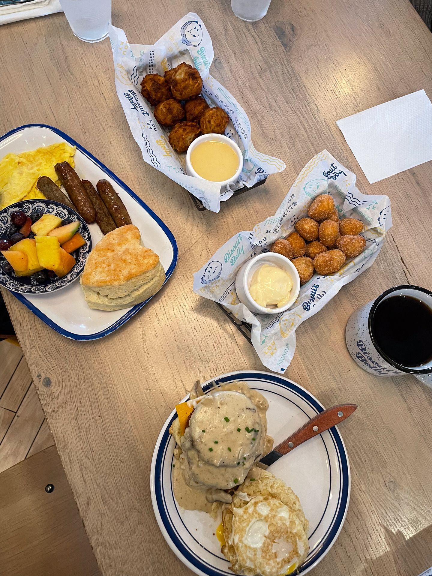 A table with multiple plates of biscuits and donut holes