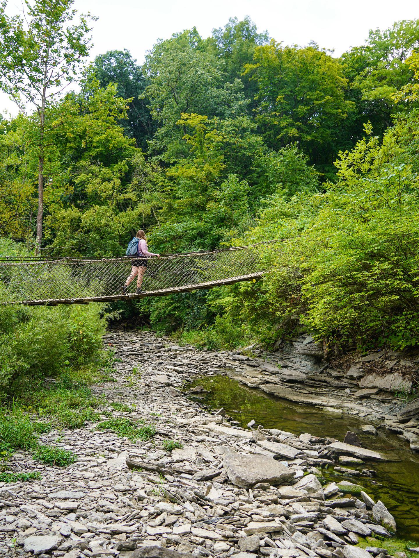 Lydia walking across a suspension bridge while hiking in Caesar Creek State Park