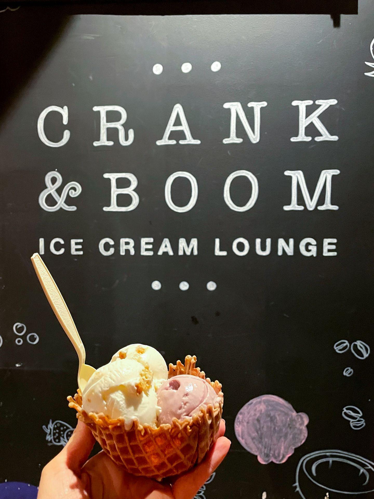 Holding up ice cream in a waffle bowl in front of a Crank and Boom sign