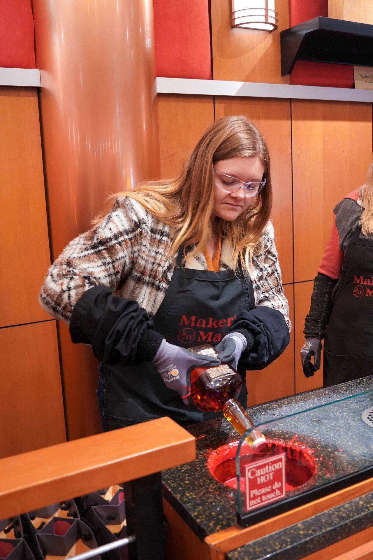 Lydia dipping a bottle of bourbon into wax at Maker's Mark