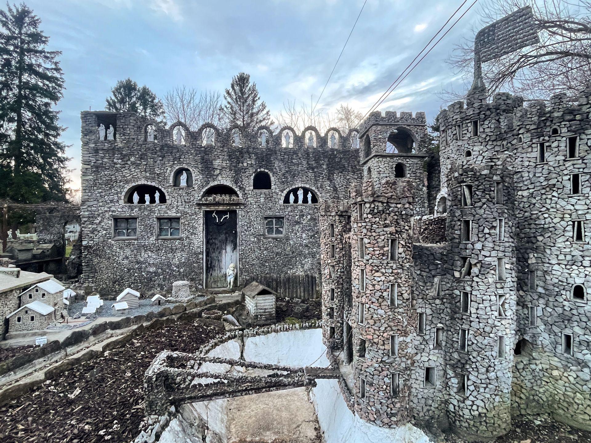 A castle built from stones with a moat and small homes surrounding it