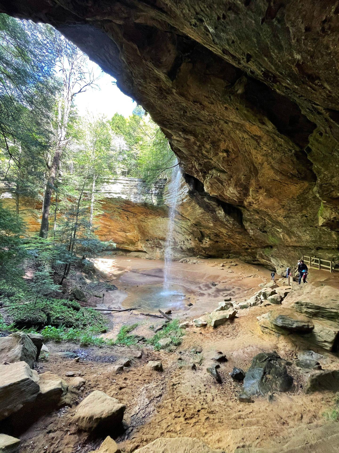 A view of Ash Cave and a waterfall coming from the top from the side of a rock cliff