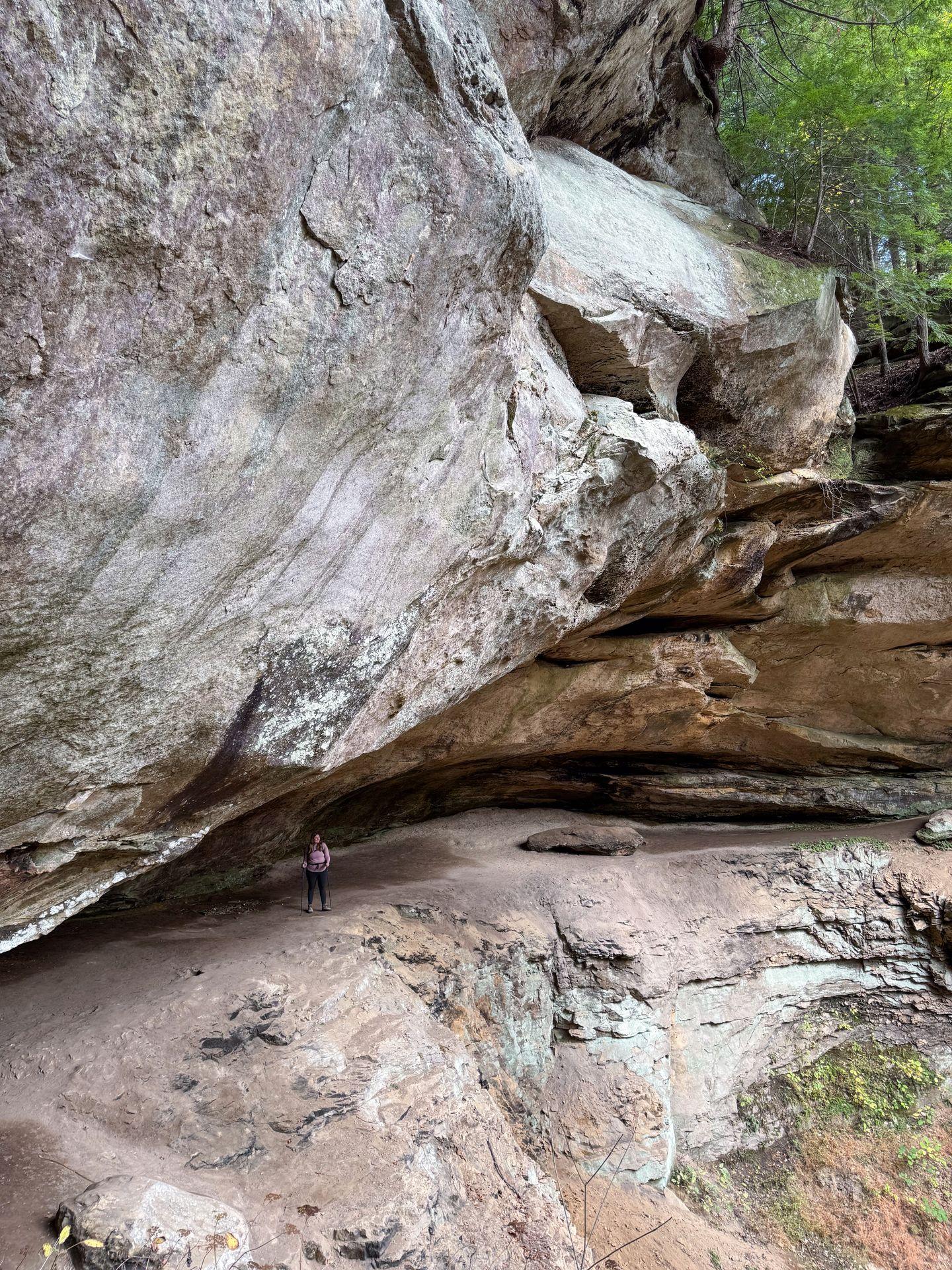 Lydia hiking under a large rock face at Hemlock Cliffs