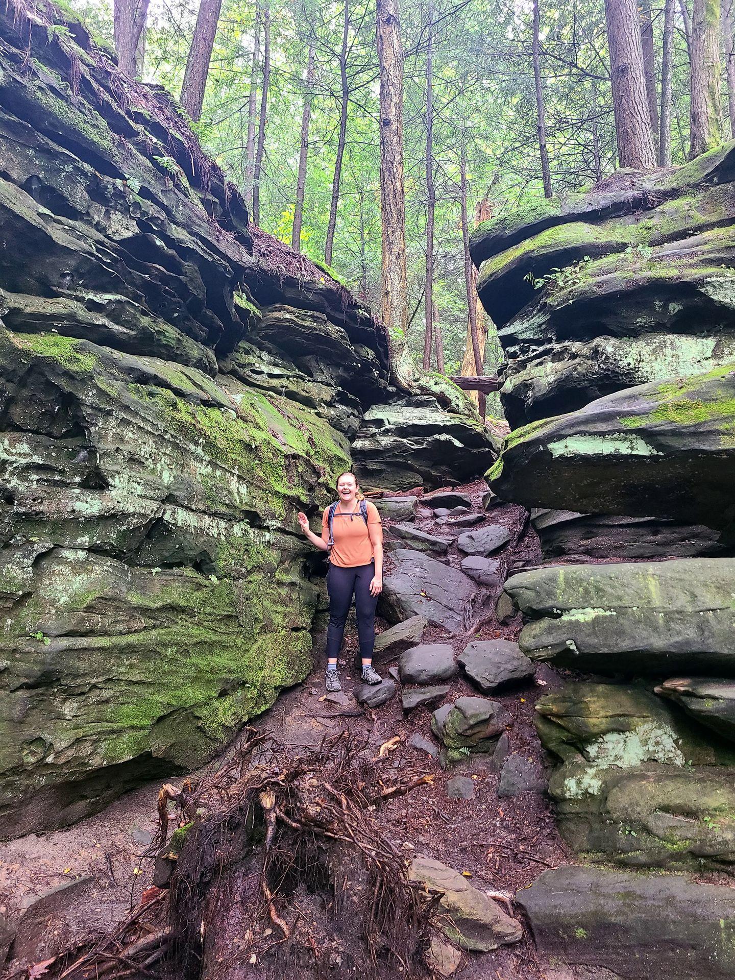 Lydia standing in the middle of two rocky ledges covered in green mosses