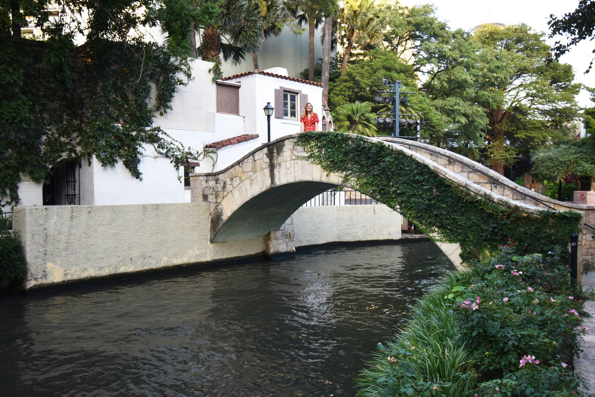 Lydia standing on a Rosita's Bridge over the San Antonio River walk. The bridge is white and has green vines hanging from it.