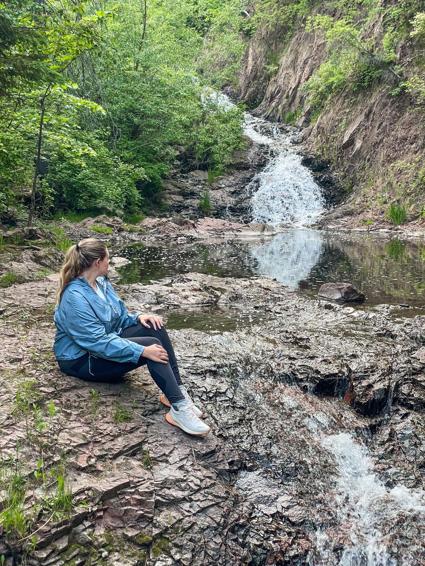 Lydia sitting and looking at the waterfall in Congdon Park