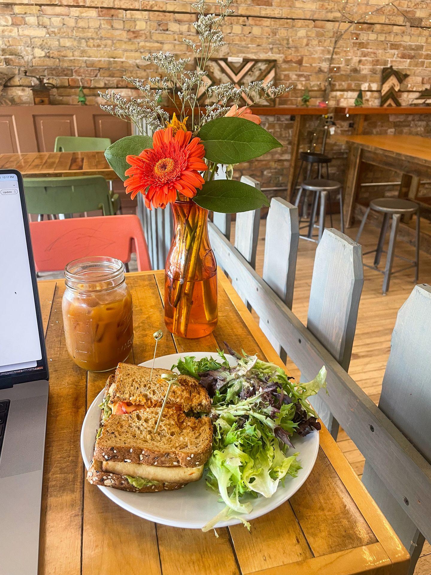 A sandwich and salad, plus an iced coffee, next to a laptop inside Dovetail Cafe & Marketplace