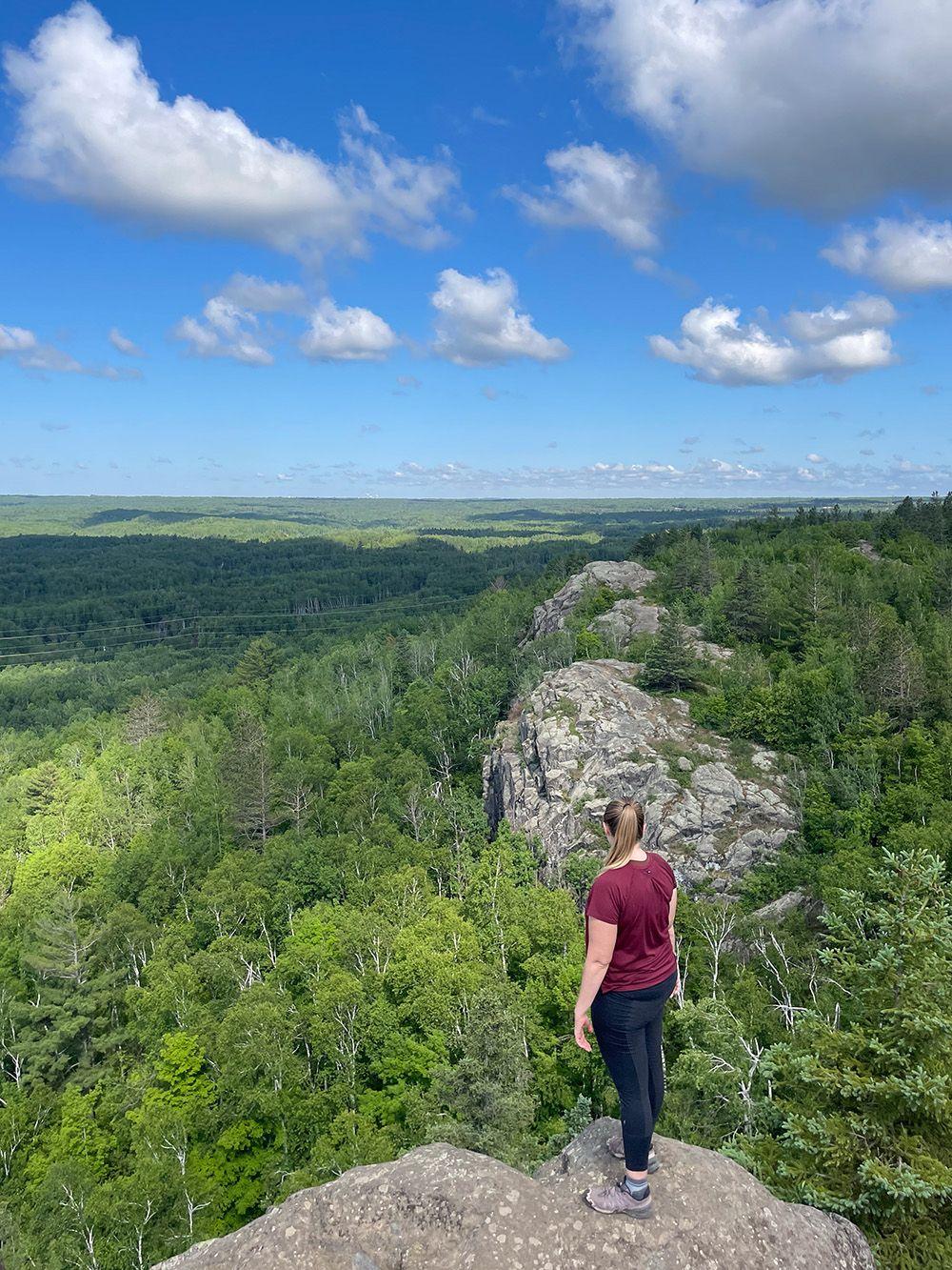 Lydia looking out at a view with green hills and white rocks from Ely's Peak