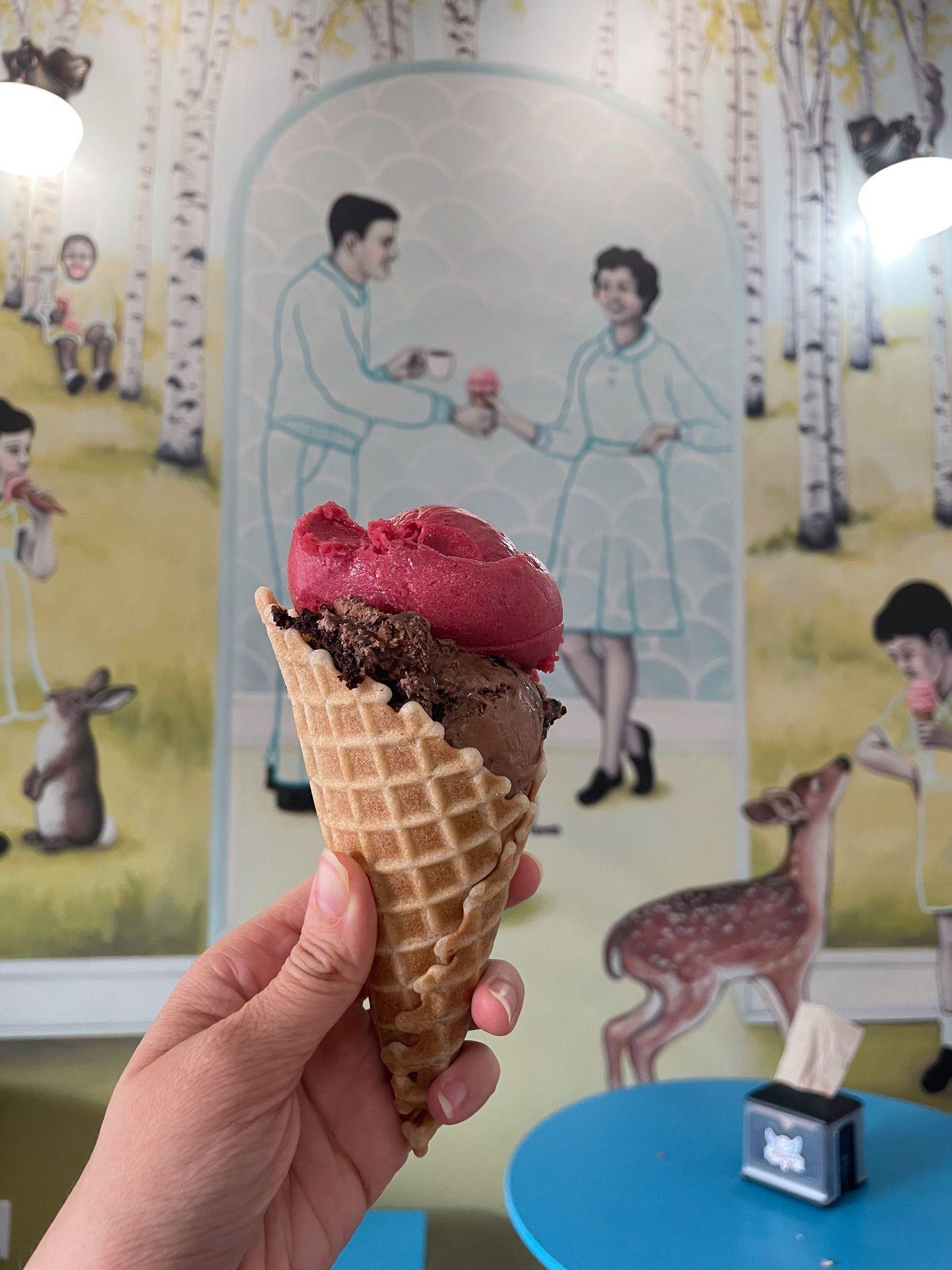 Holding up a waffle cone with chocolate and raspberry ice cream from Love Creamery