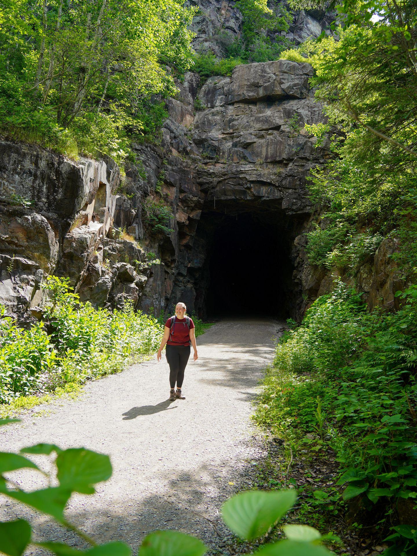 Lydia walking out of a former railroad tunnel on the Ely's Peak Trail