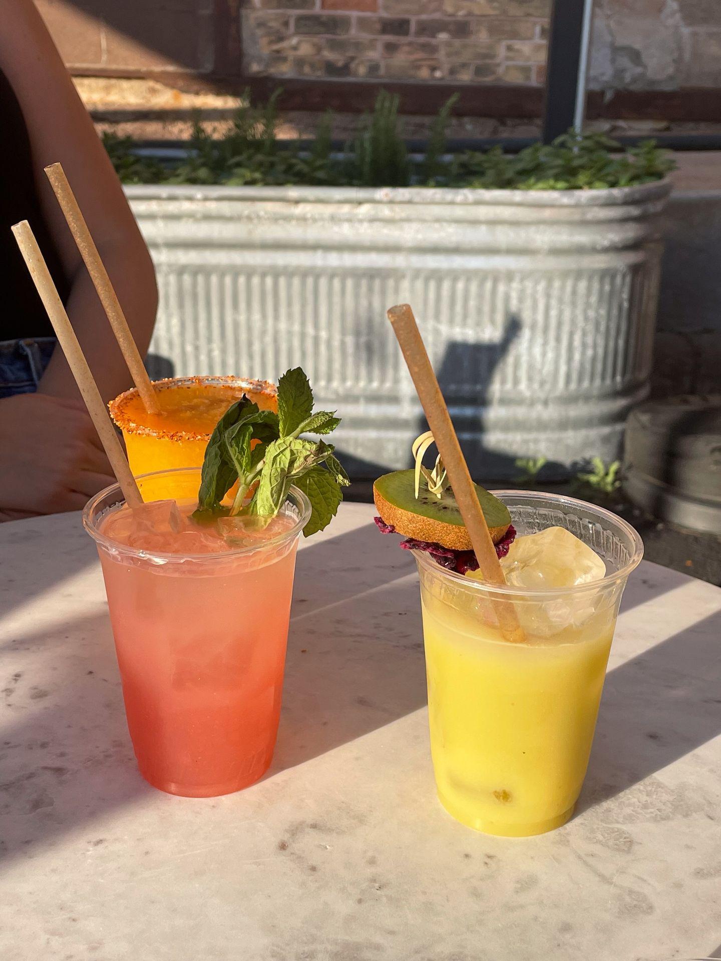 Three cocktails sitting on a table from Vikre Distillery. One is yellow, one is orange, one is pink