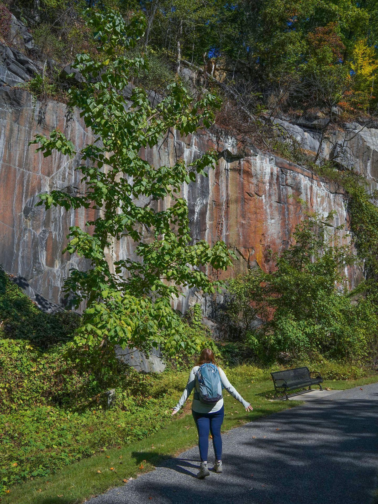 Lydia looking towards a granite cliff with orange, yellow and red stripes