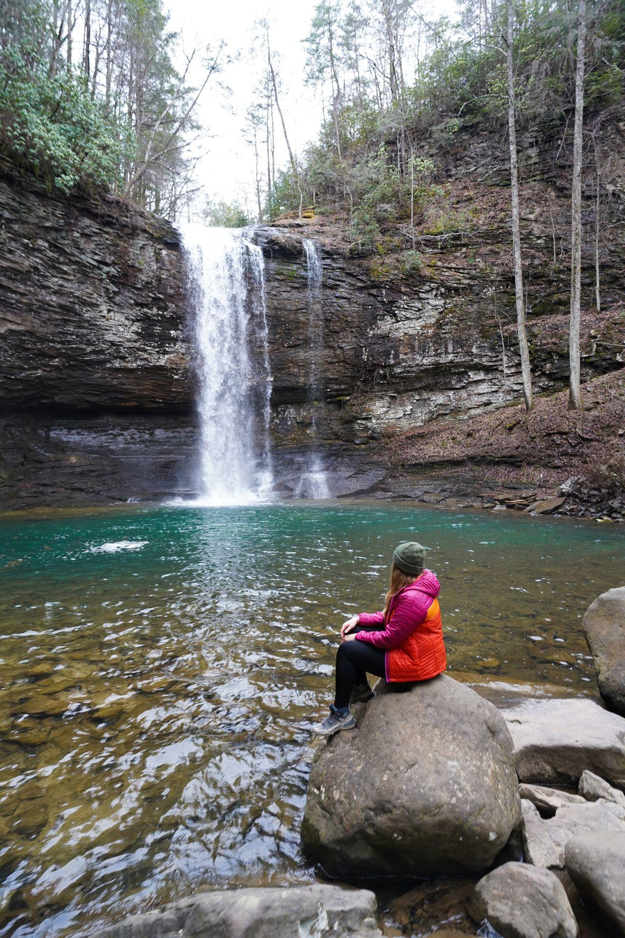 Lydia sitting on a rock and looking out at a waterfall in Cloudland Canyon State Park