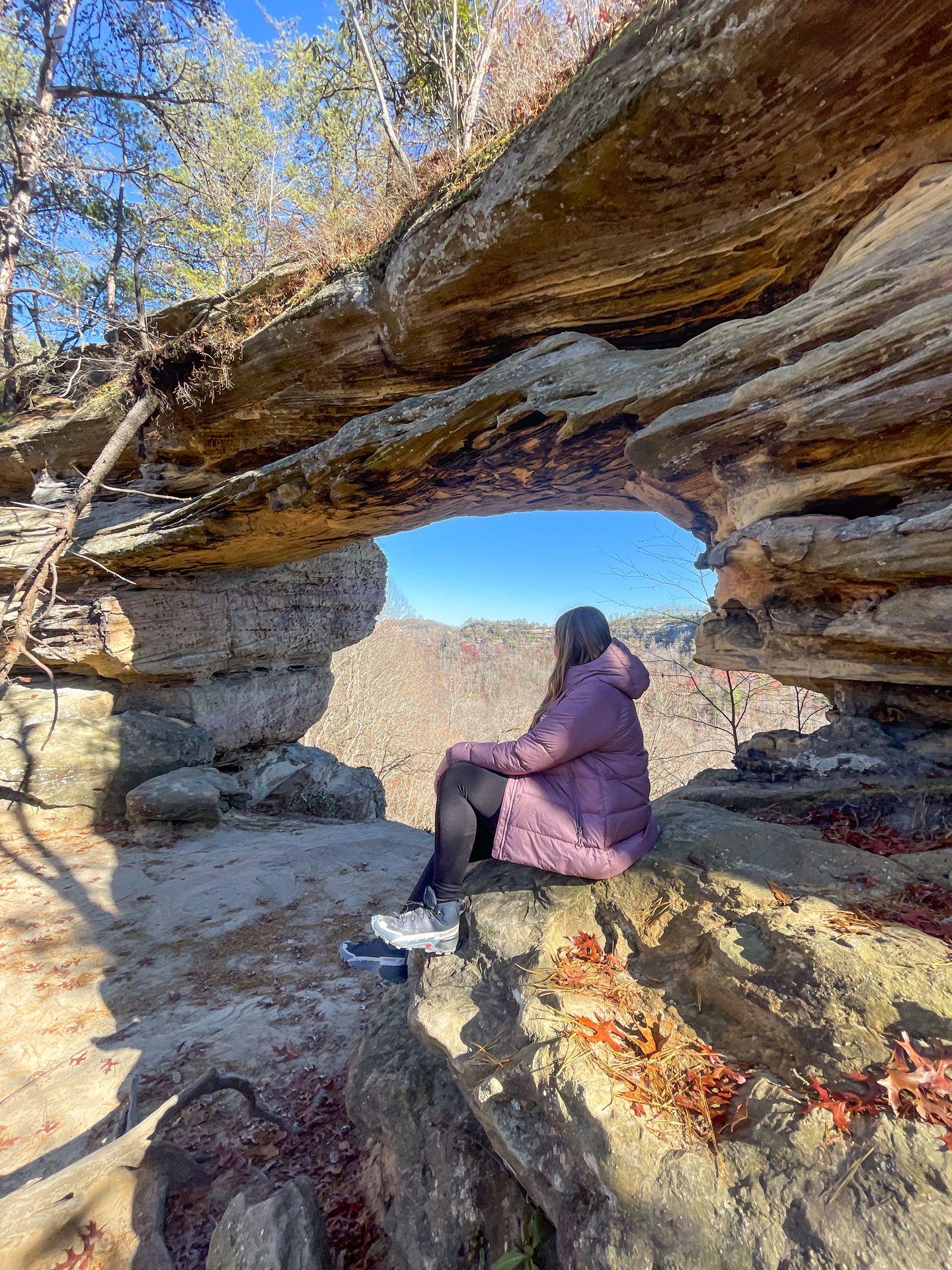 Lydia sitting and looking at Double Arch in Red River Gorge