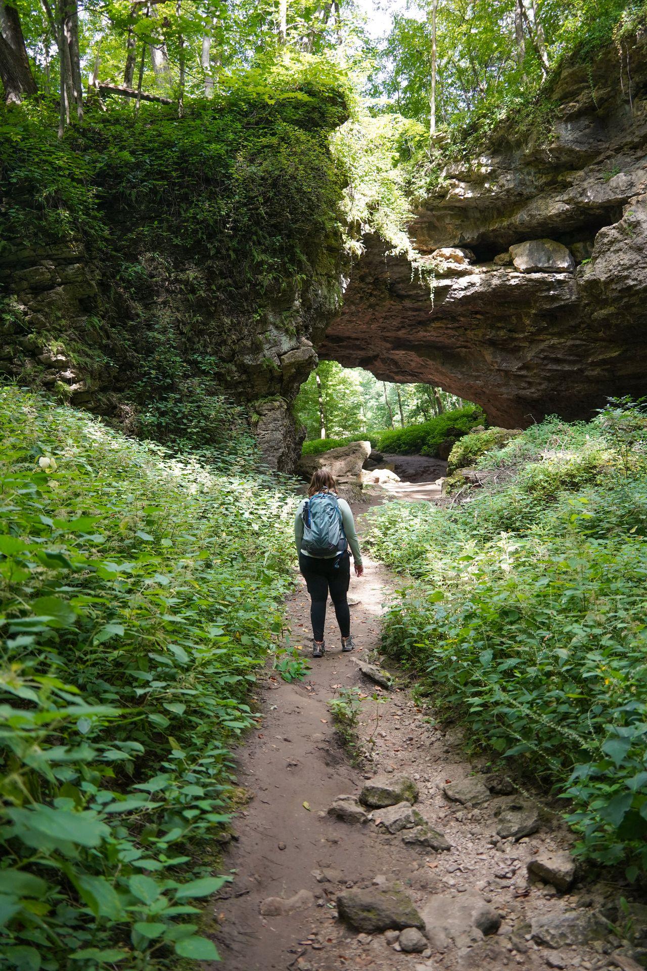 Lydia walking towards a large natural bridge in Maquoketa Caves State Park