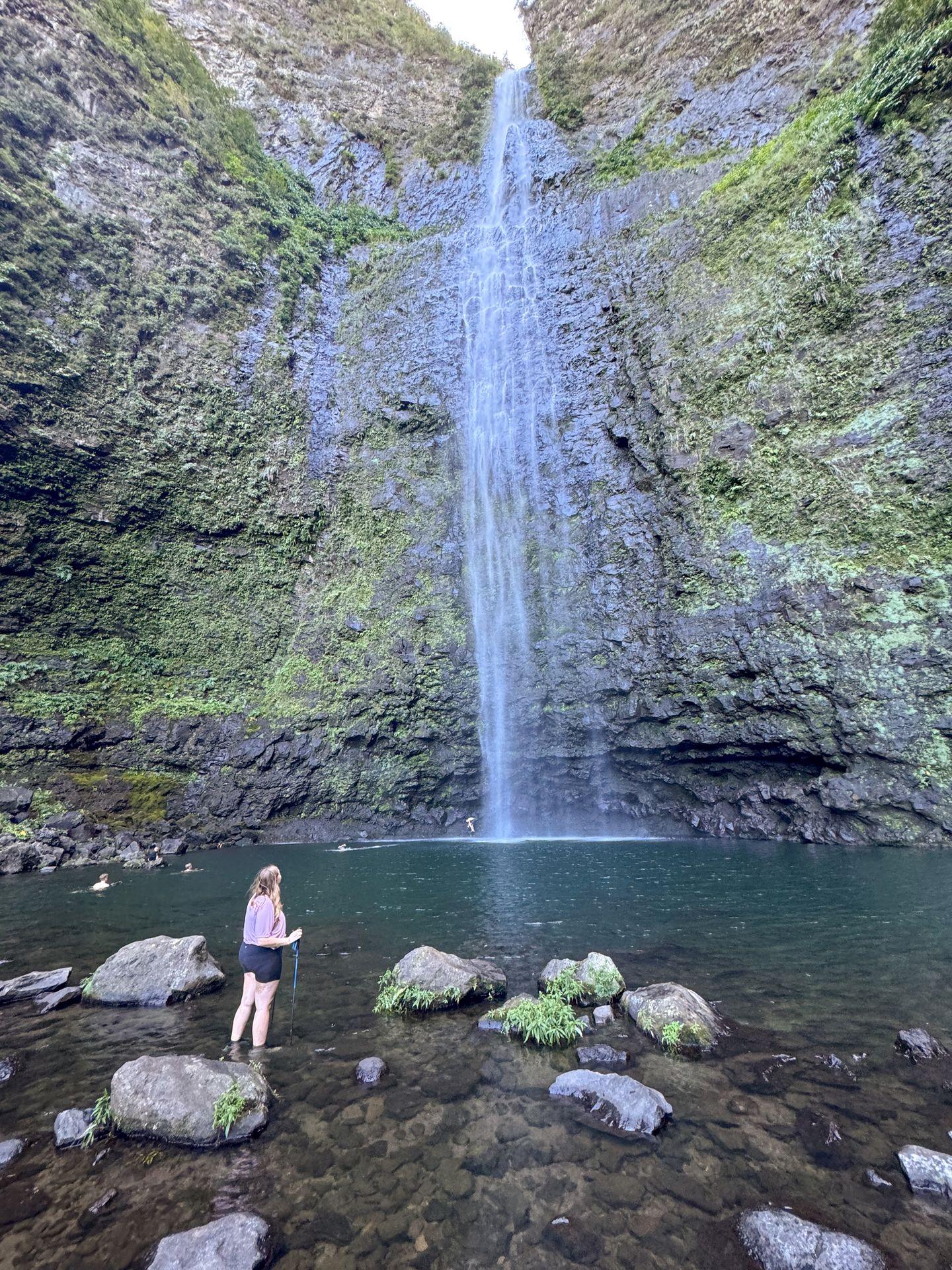 Lydia looking up at Hanakāpīʻai Falls, which flows down a tall cliff face