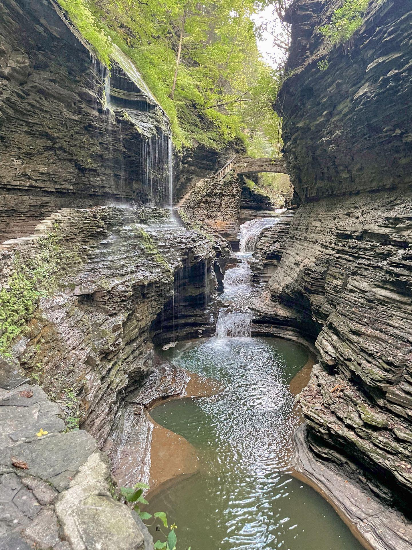 Looking at a waterfall below a stone bridge in the center of a gorge at Watkins Glen