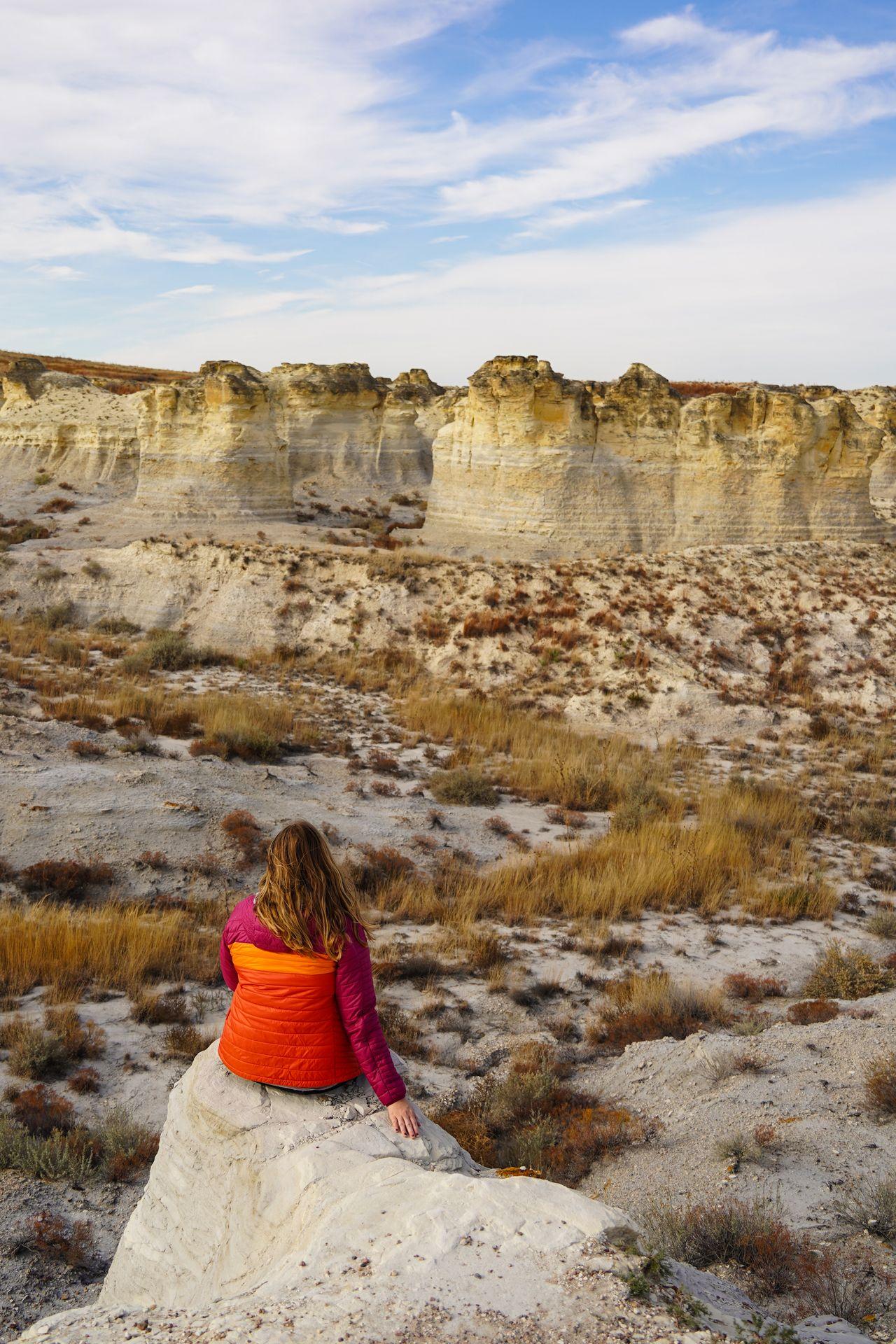 Lydia sitting on a rock and looking out at a view of the badlands on the Overlook Trail