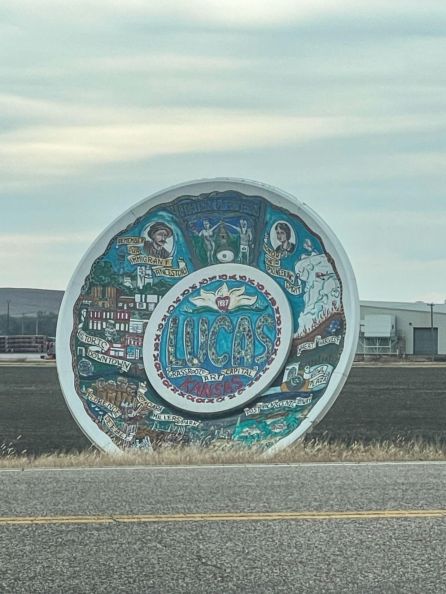 A huge painted travel plate that showcases information about Lucas, Kansas