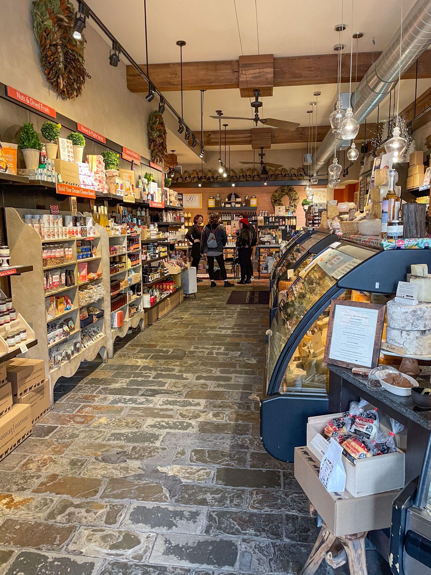 The interior of Fromagination. The store has cold cases of cheeses and shelves full of crackers, jams and other charcuterie items.