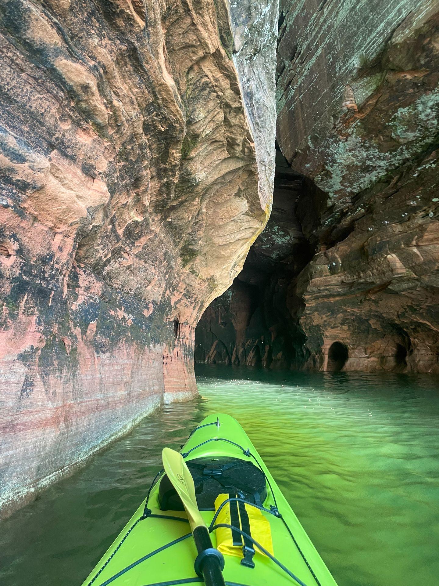 The front of a green kayak in front of a sea cave at the Apostle Islands National Lakeshore