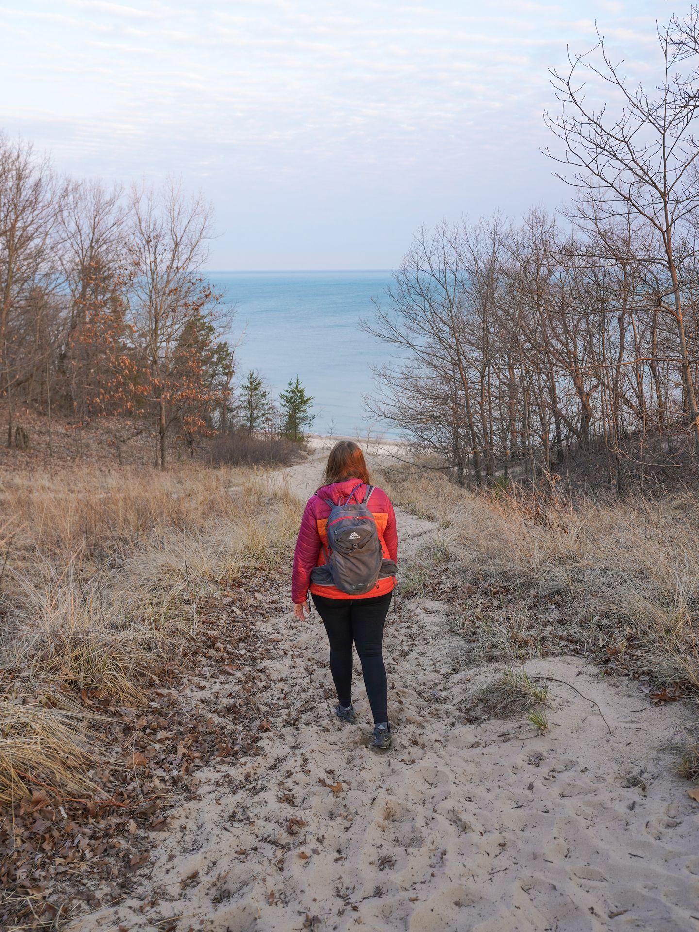 Lydia hiking on sand towards the water at Indiana Dunes