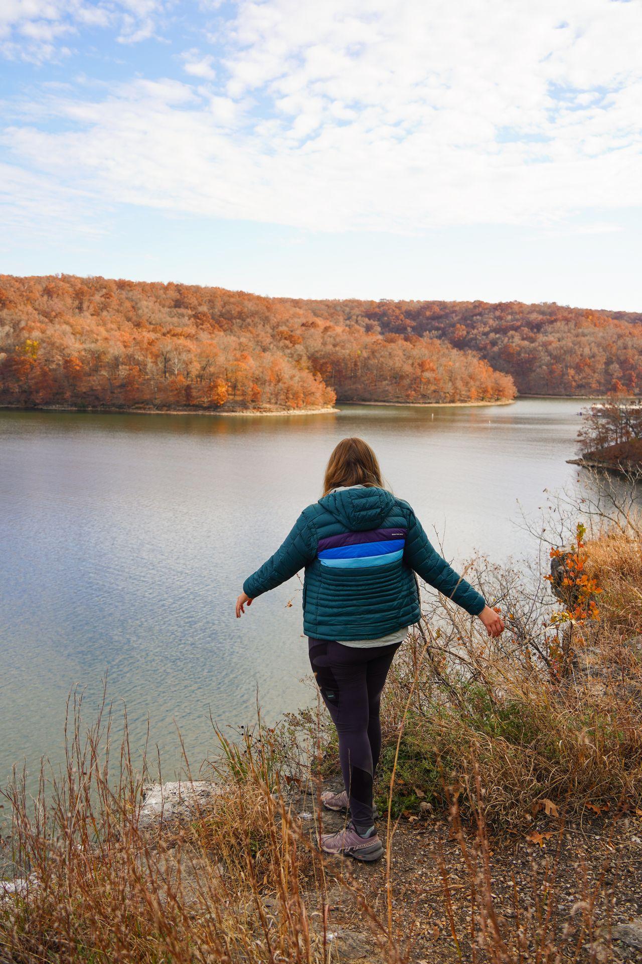 Lydia looking at the view of the lake. Trees are orange with fall foliage