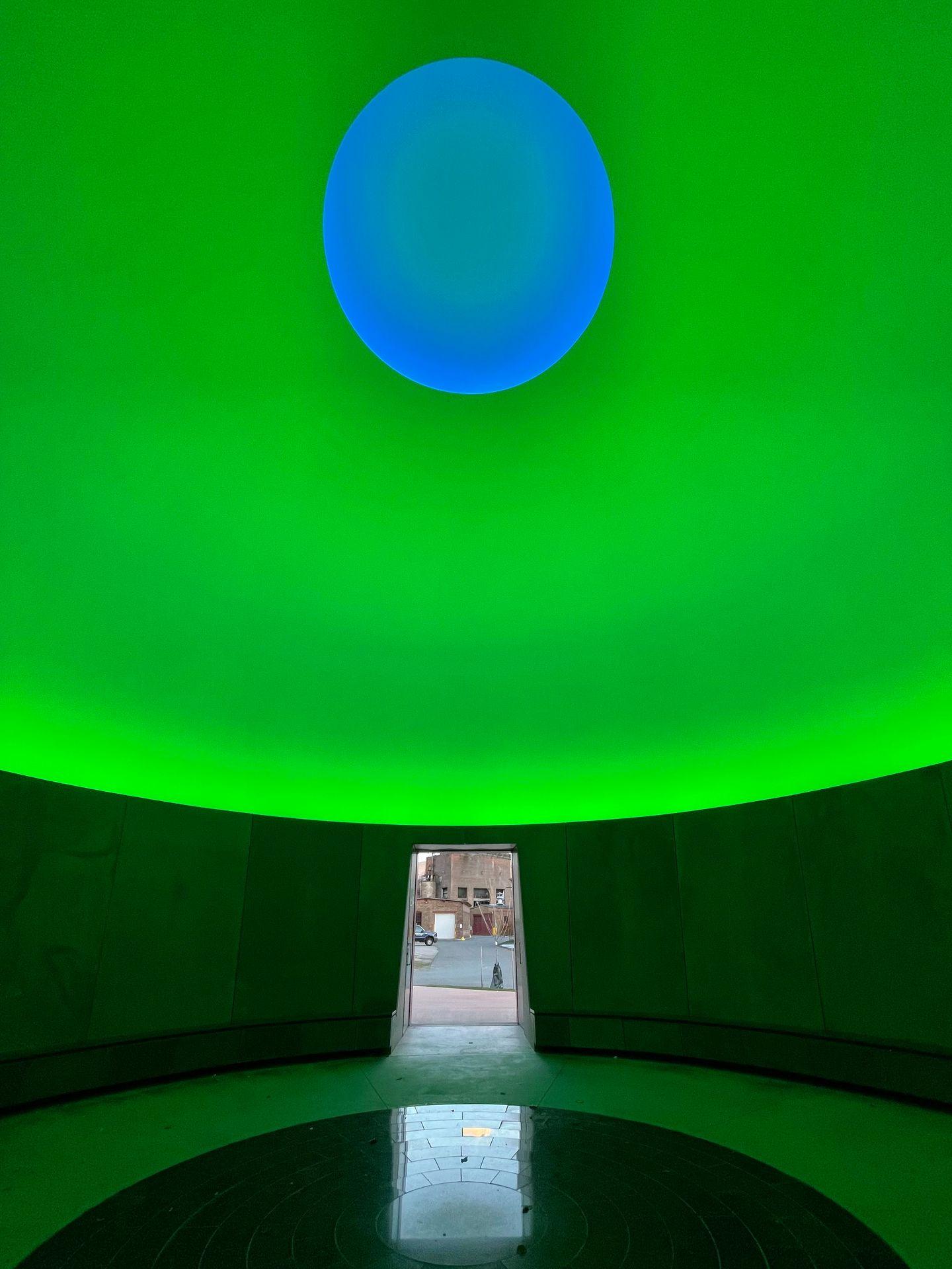 A room full of green light with a blue portal at the top