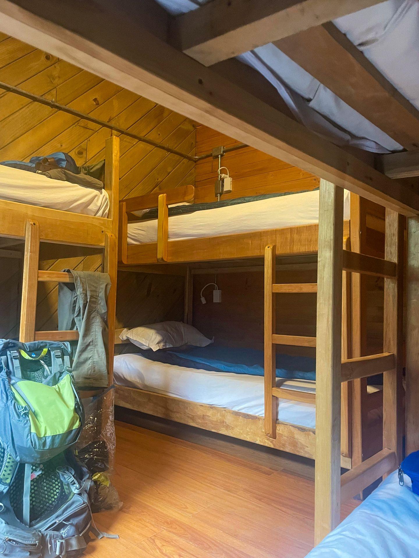 A room with 3 bunkbeds inside of the El Chileno hostel. A large hiking backpack sits on the ground.