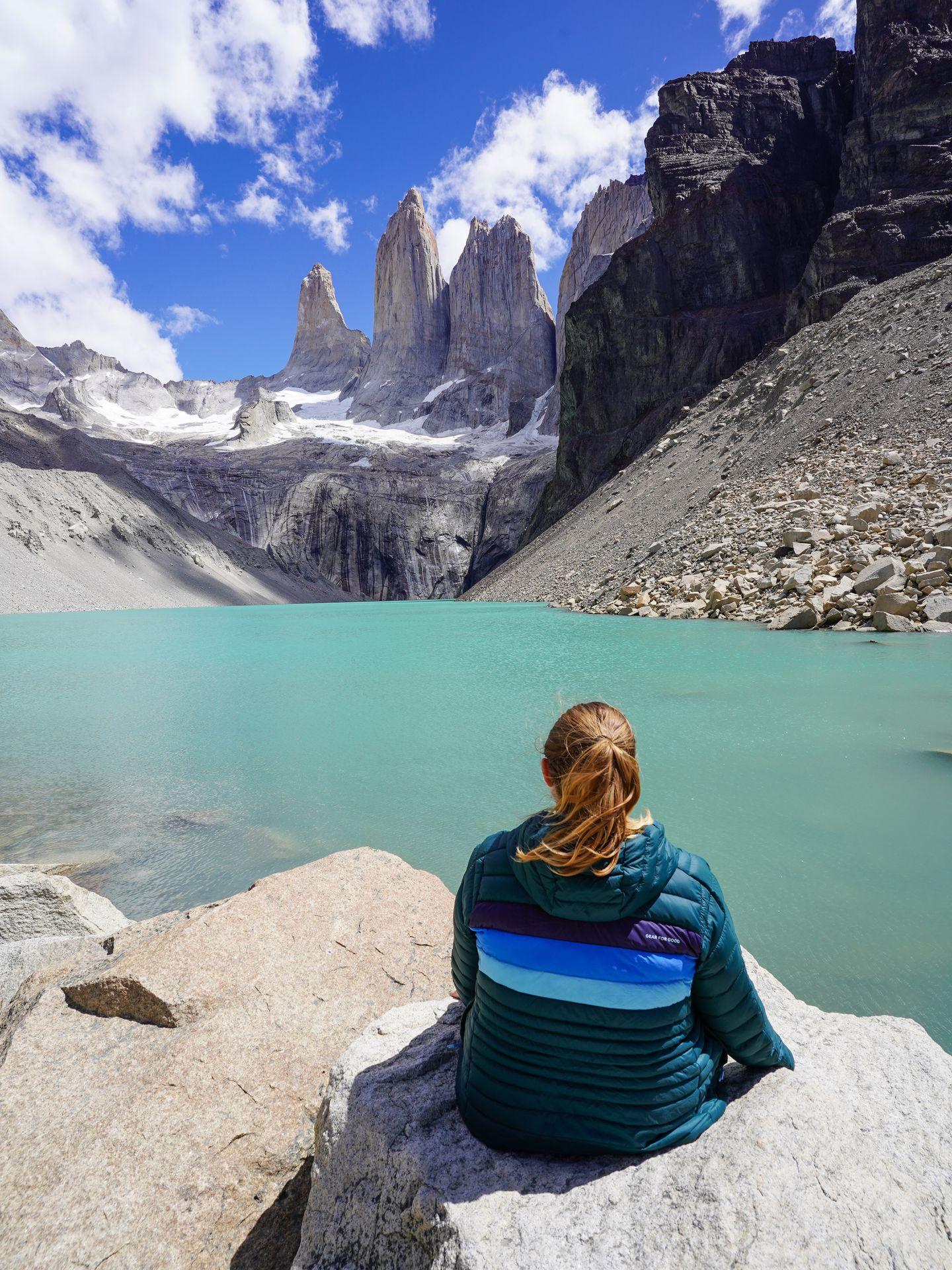 Lydia sitting on a rock and looking out at the Towers, 3 mountain peaks in Torres Del Paine National Park.