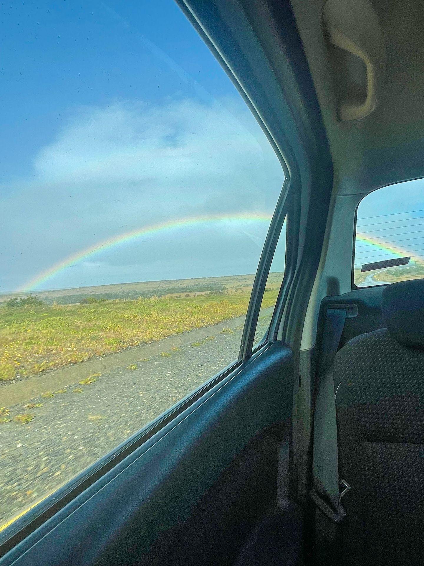 A large rainbow from the window of a rental car while driving in Patagonia.