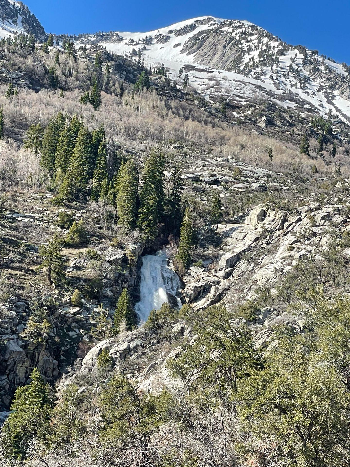 A view of the waterfall in the distnace with a snow-capped mountain above it