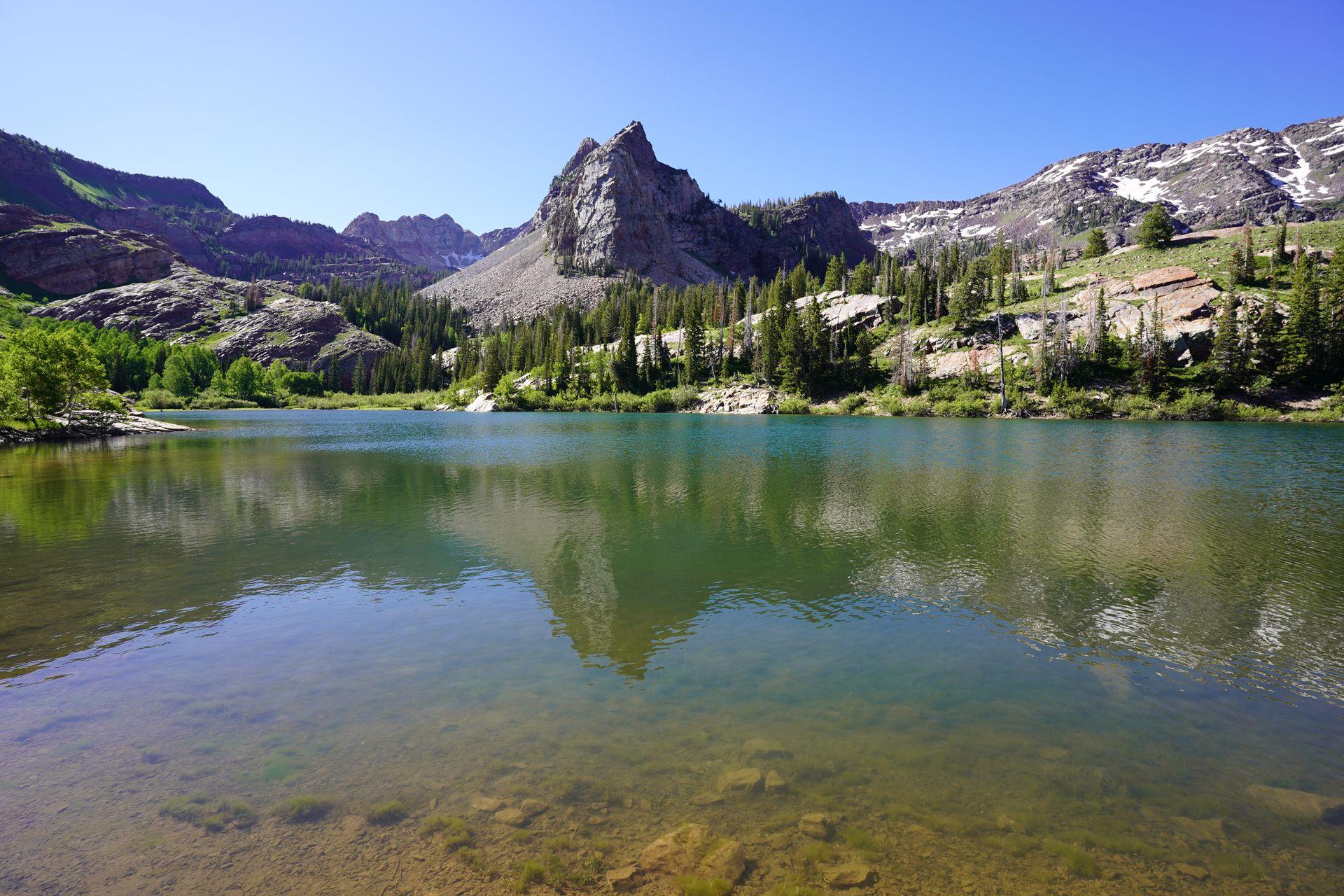 A view of Lake Blanche. There is a reflection of a pointed mountain in the water.