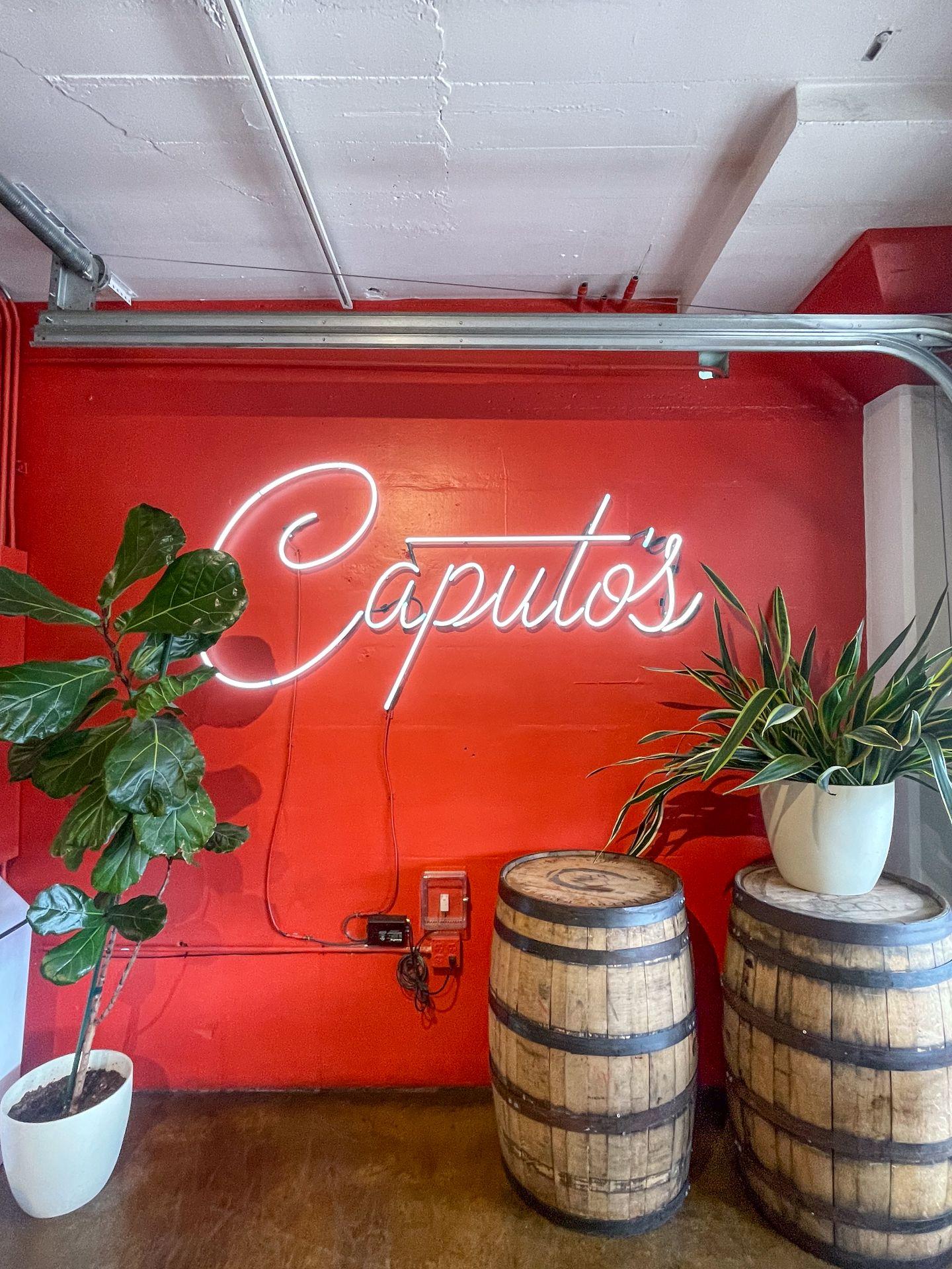 A neon Caputo's sign on a red wall