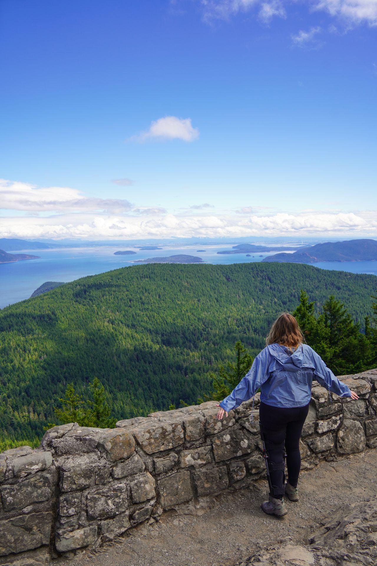 Lydia standing at a stone wall and looking out at the view from Mount Constitution