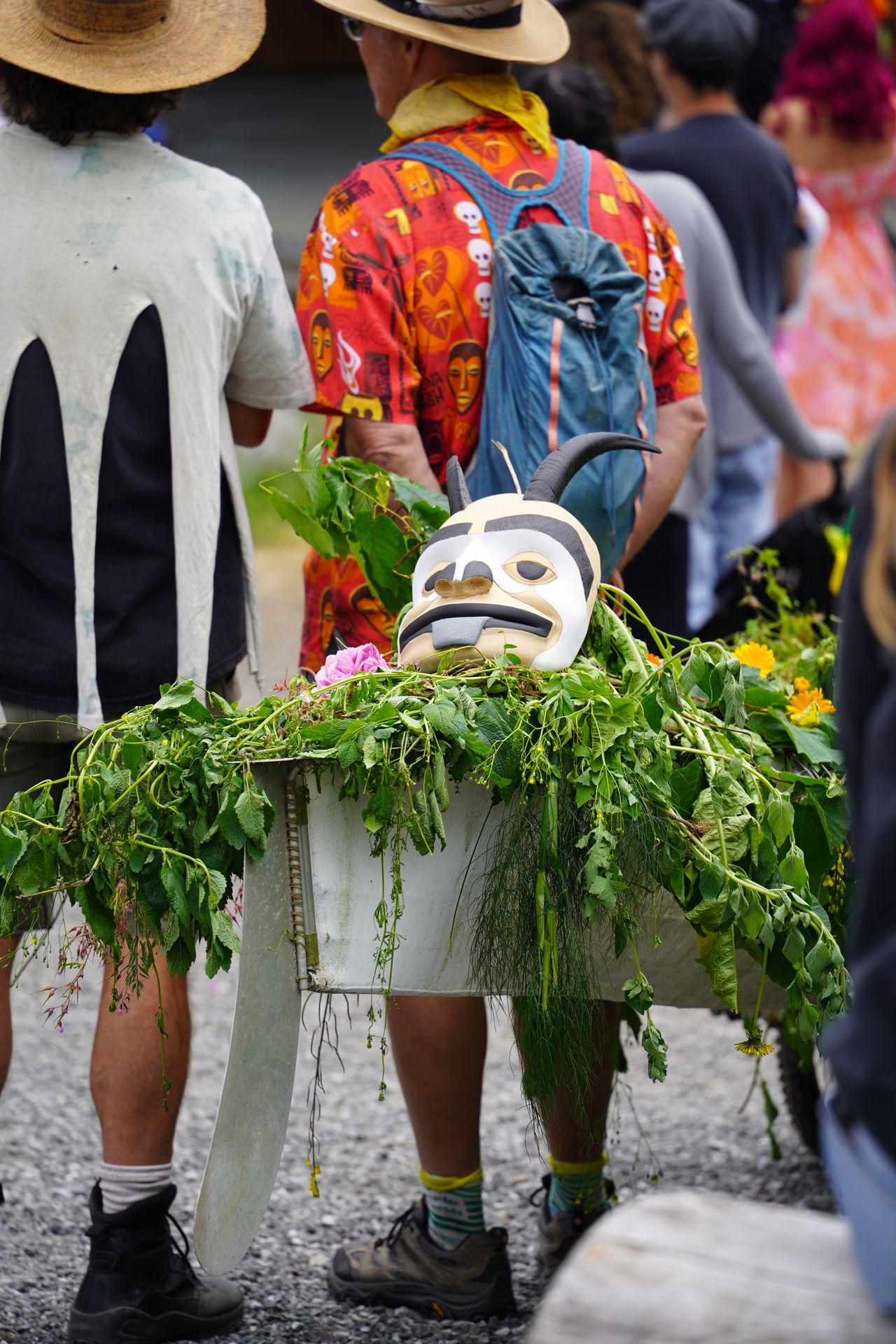 A canoe full of greenry with a mask on top