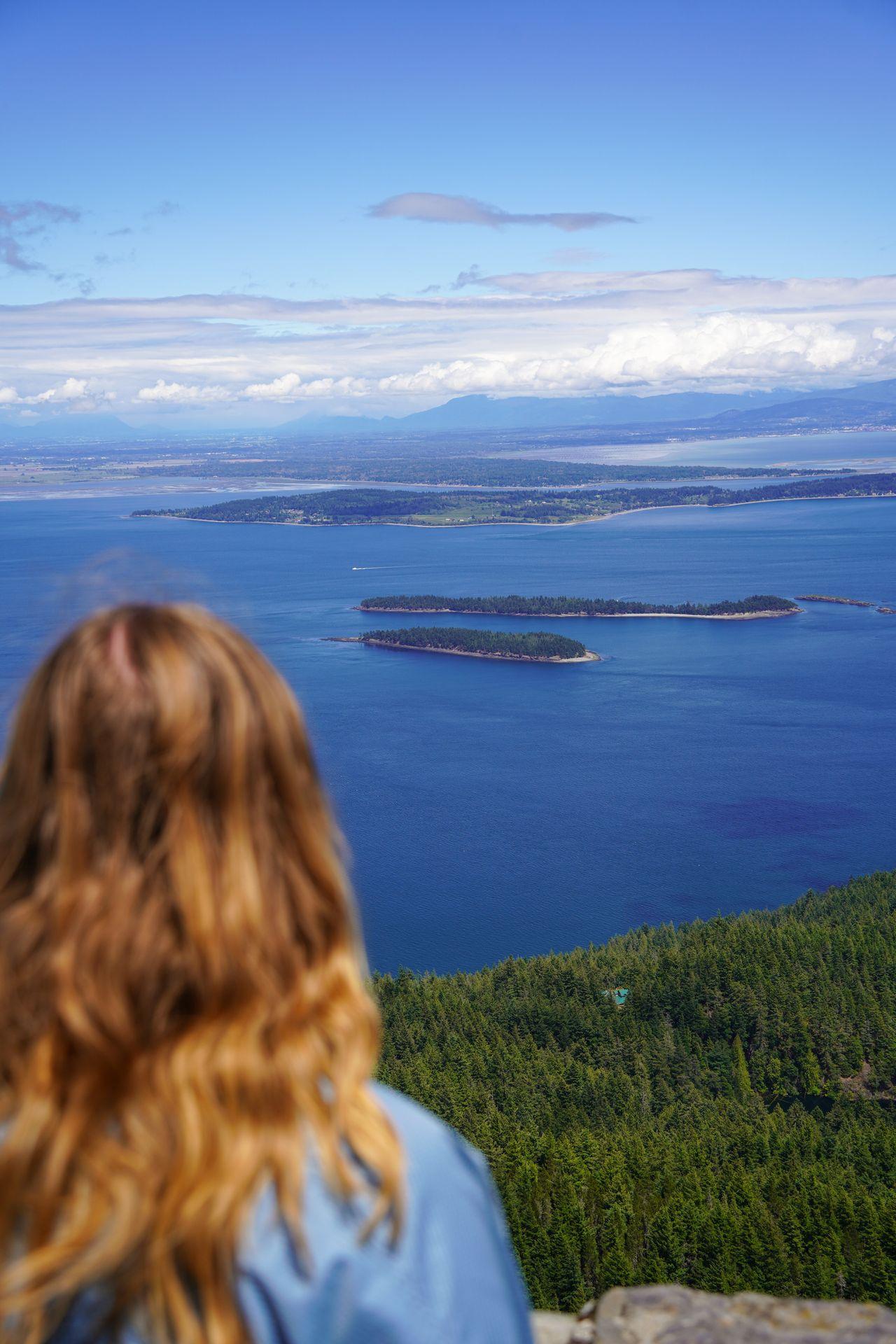 The back of Lydia's head and she looks out at the view from the top of Mount Constitution