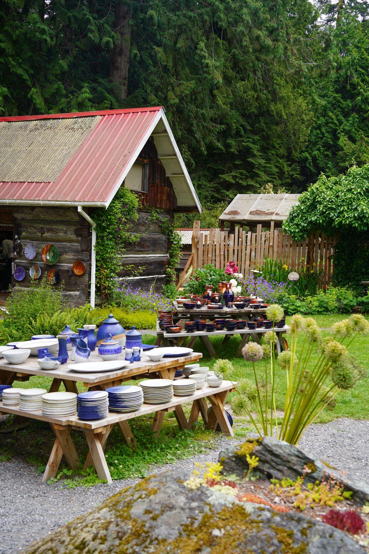 A garden space with tables full of pottery at Orcas Island Pottery