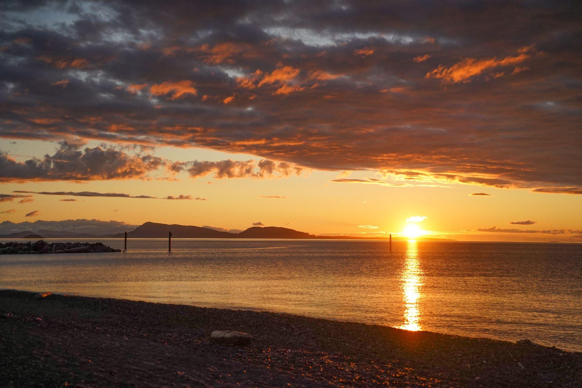 The sun setting over the ocean with hills in the distance, seen from the north side of Orcas Island