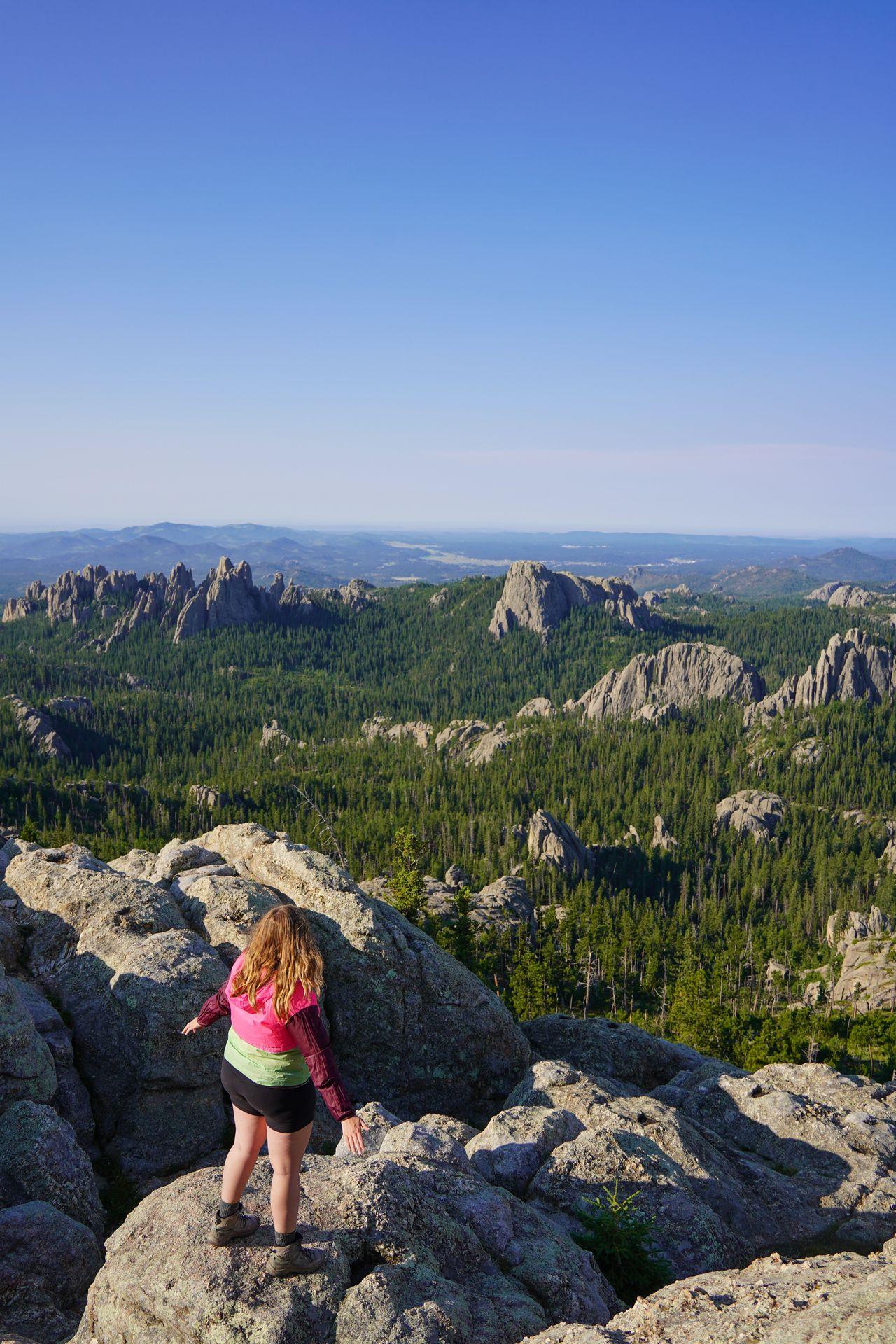 Lydia looking out at jagged, gray rocks and greenery from Black Elk Peak in Custer State Park