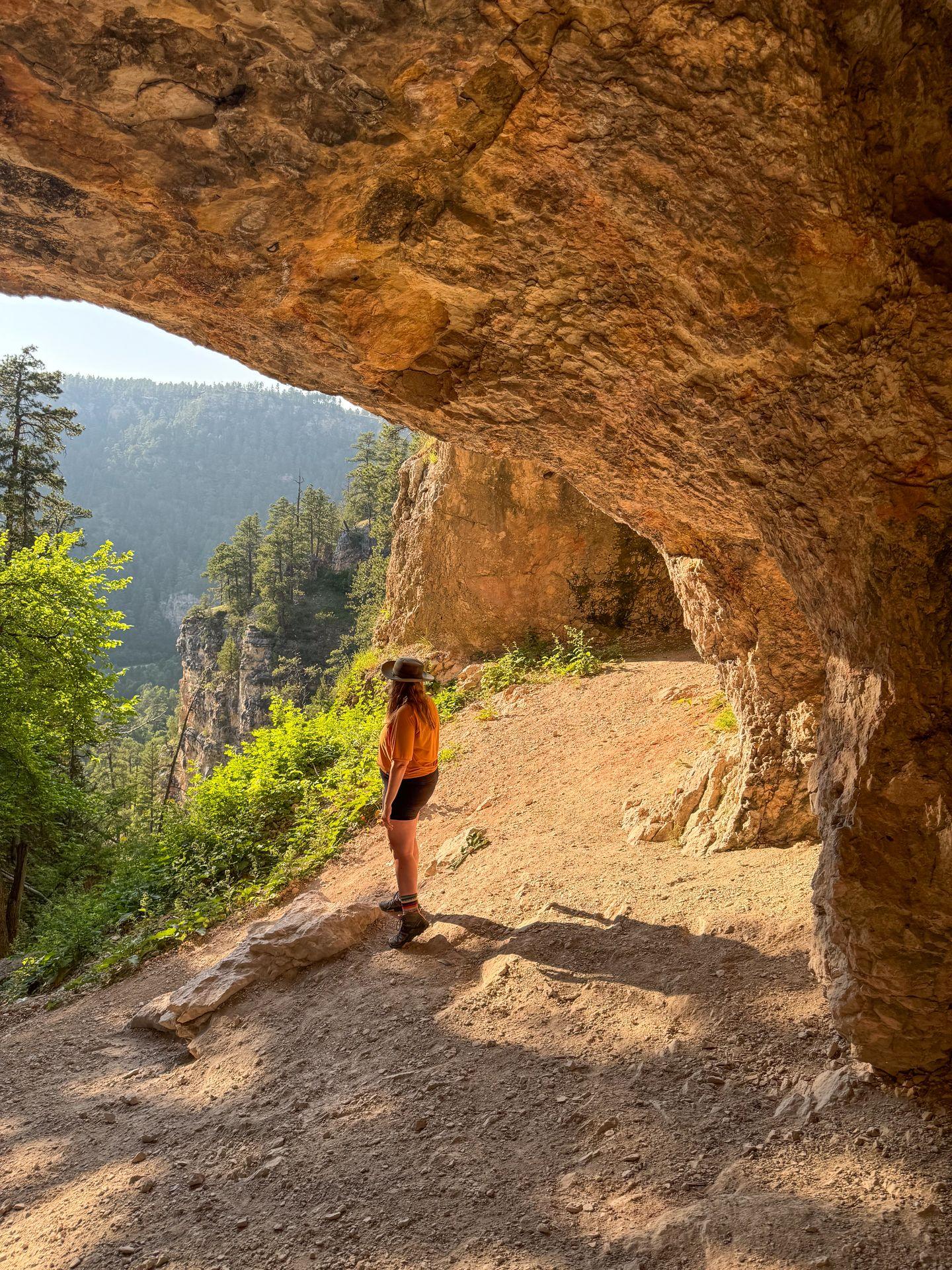 Lydia standing in a cave and looking out a view in Spearfish Canyon