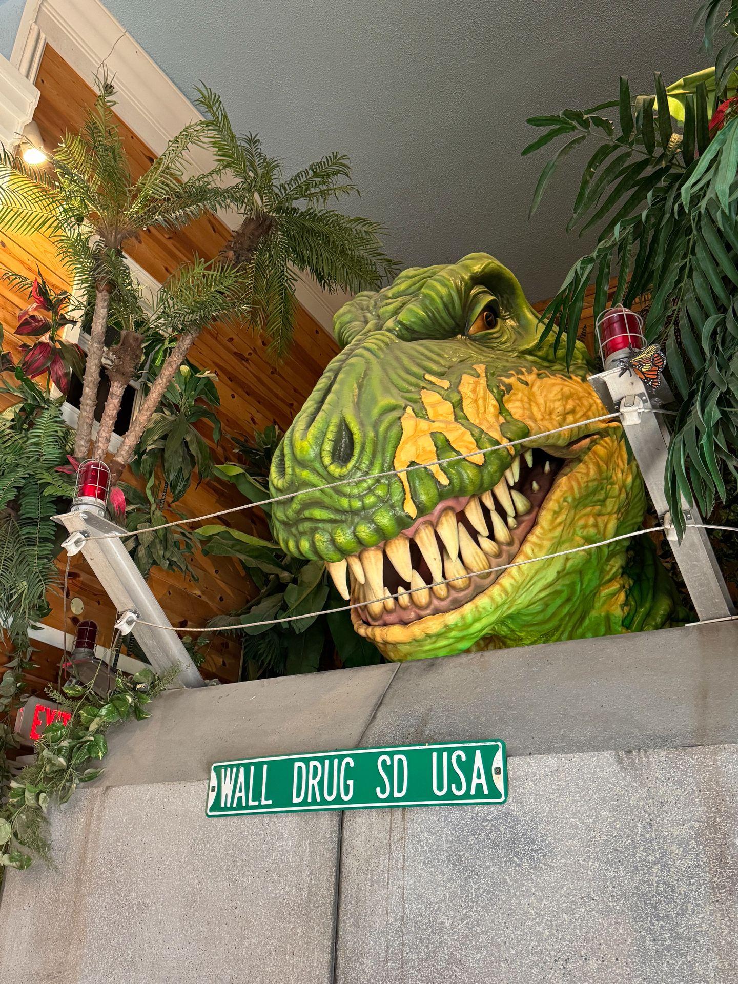 The head of dinosaur above a sign that reads "Wall Drug SD USA"