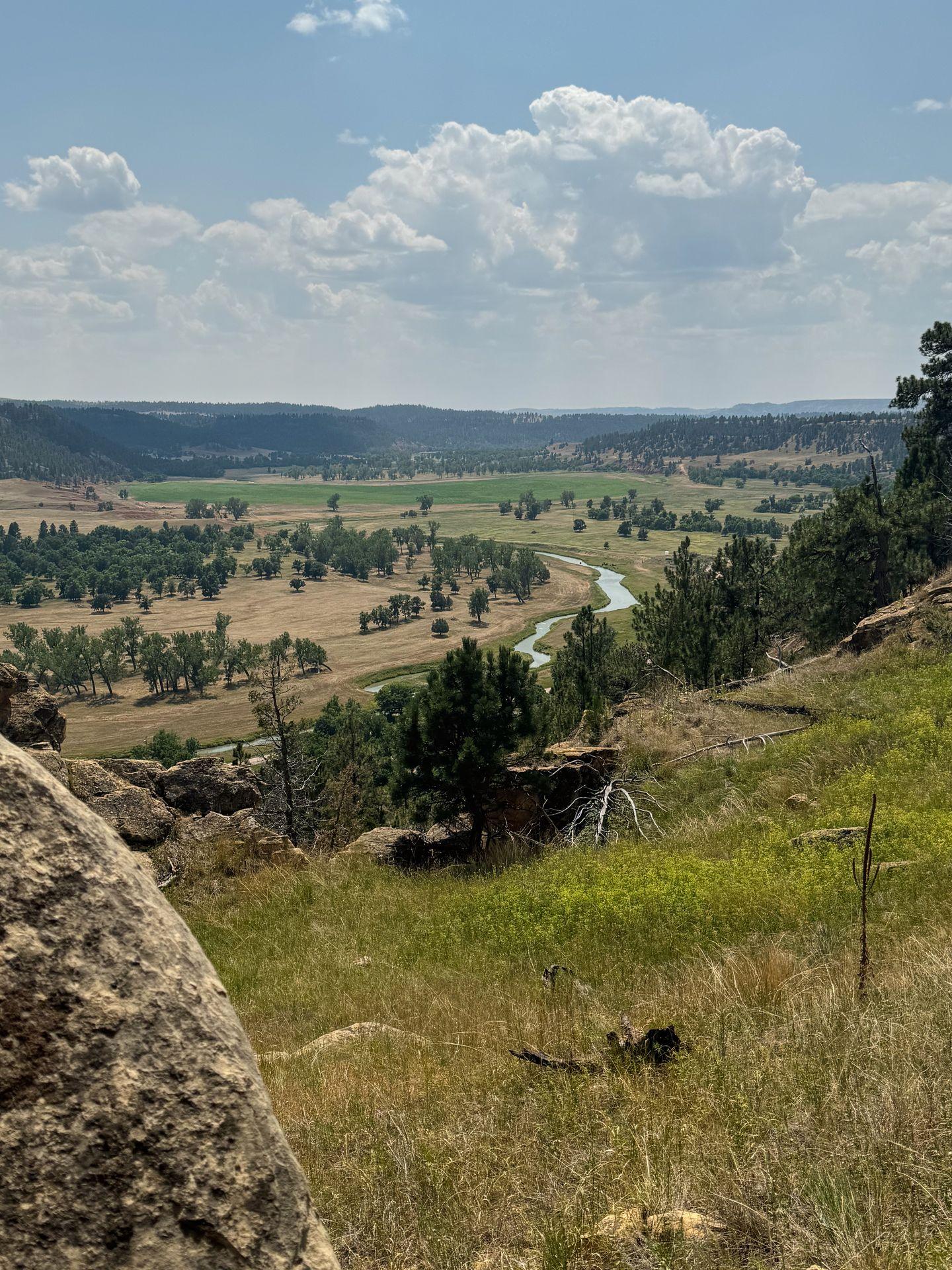 A view of a river and the valley down below, seen from the trail around Devil's Tower