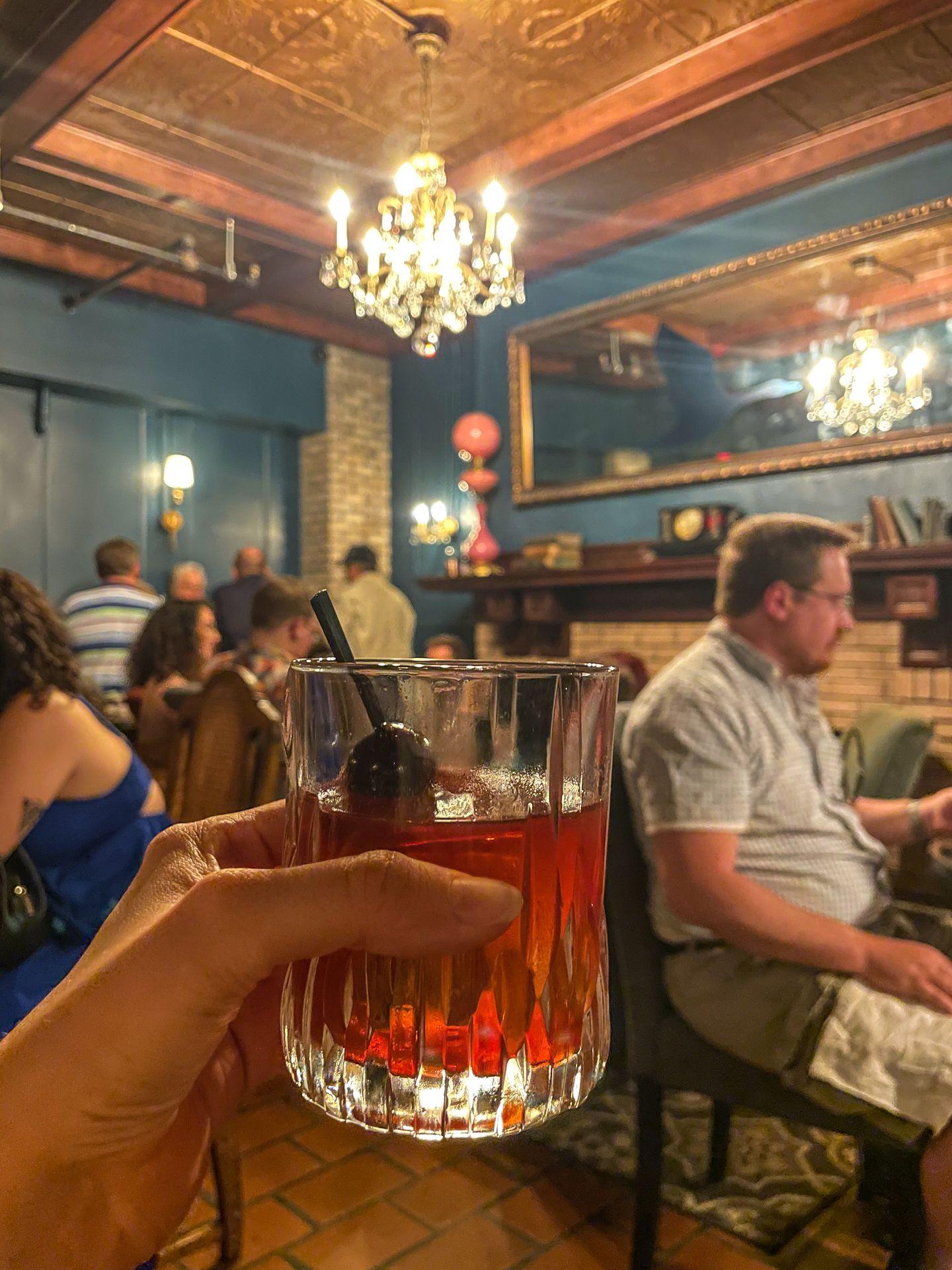Holding up an old fashioned cocktail in the Blue Goose Speakeasy